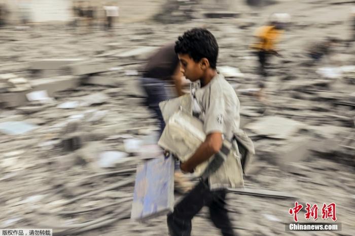 沙地带南部拉法地区的废墟中，一名儿童在断壁残垣中搜寻可用的物品